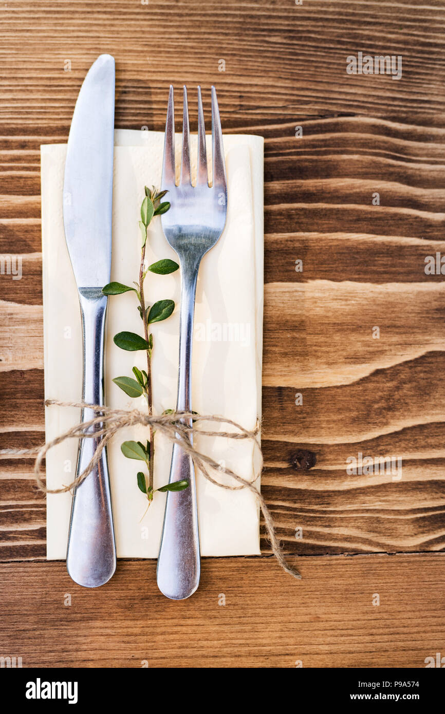 Un coltello e forchetta su un tovagliolo su un marrone, un tavolo di legno. Vista dall'alto. Foto Stock