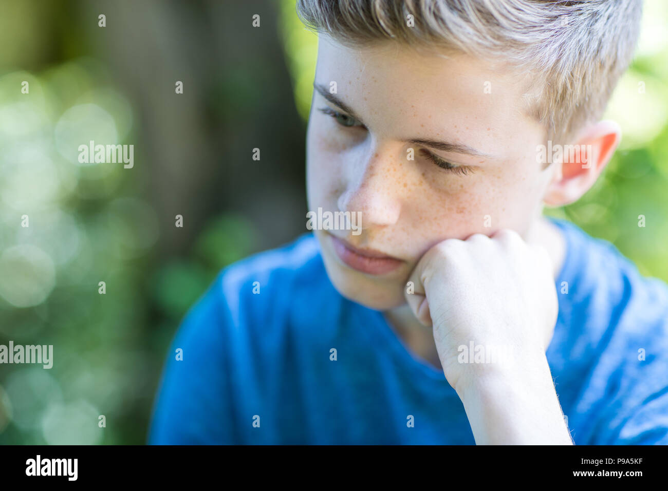 Close up infelice ragazzo adolescente seduti all'aperto Foto Stock