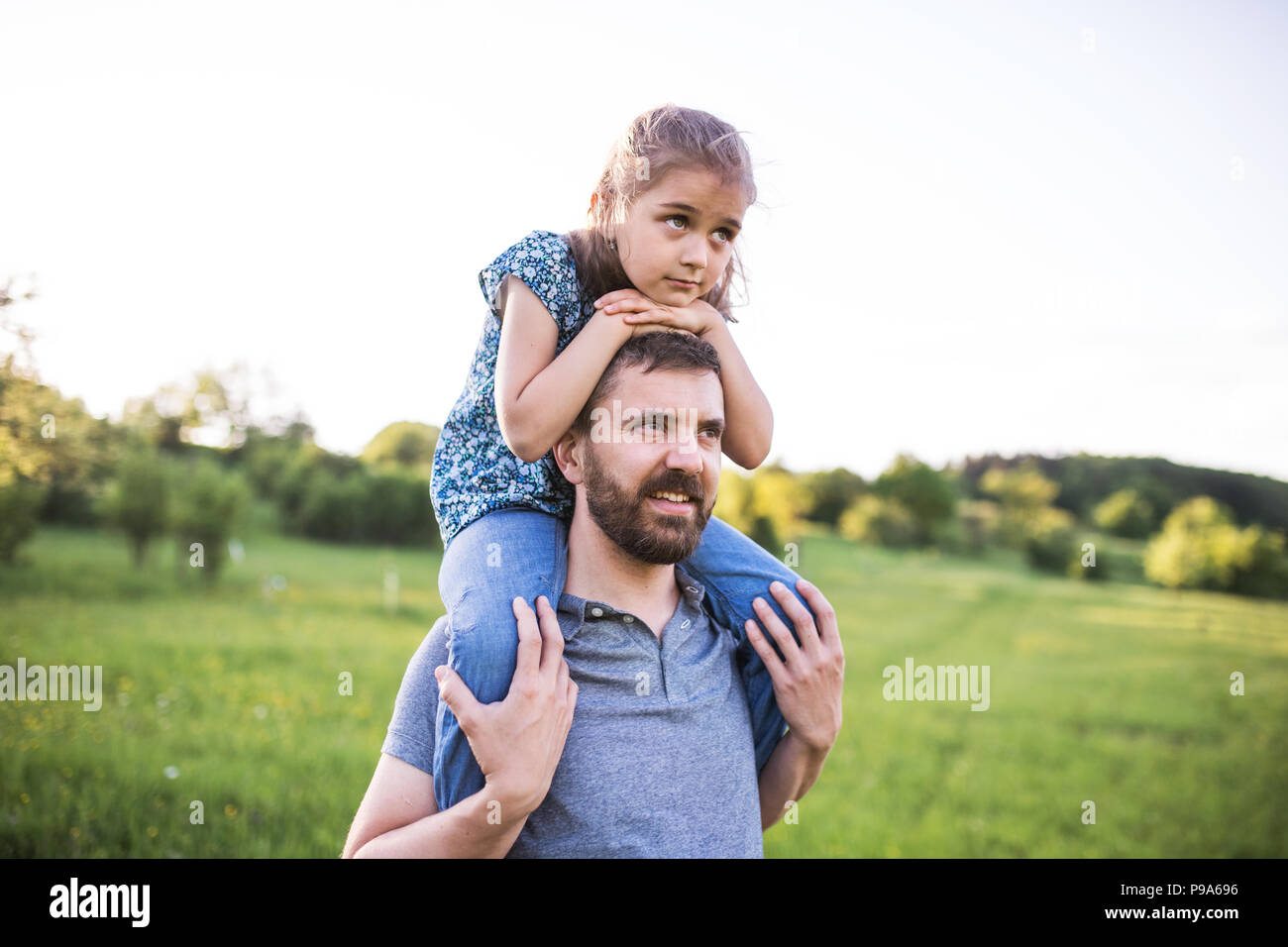 Padre dando piccola figlia di un piggyback ride in primavera la natura. Foto Stock