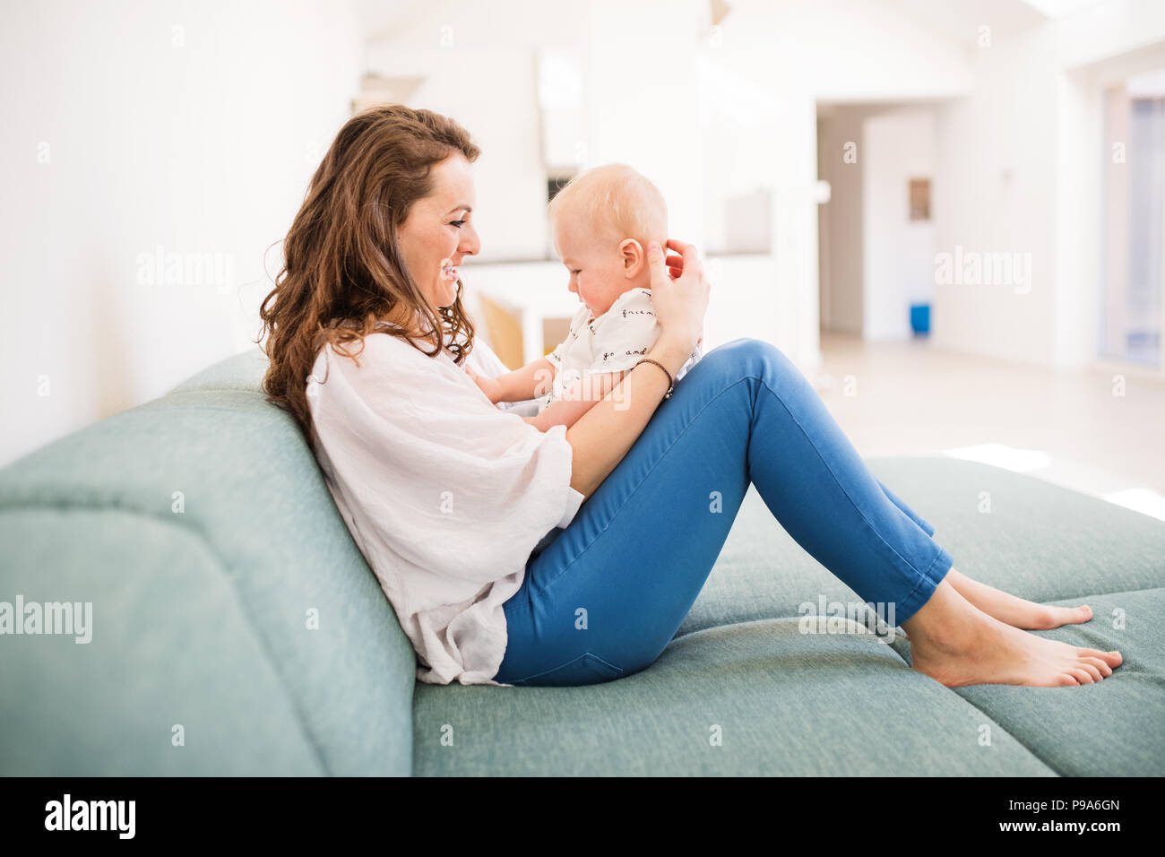 Giovane madre con un bambino a casa seduti sul divano. Foto Stock