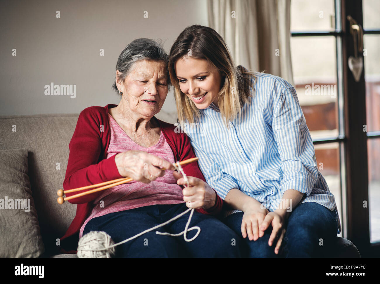 Nonna e nipote di adulto a casa, lavorazione a maglia. Foto Stock