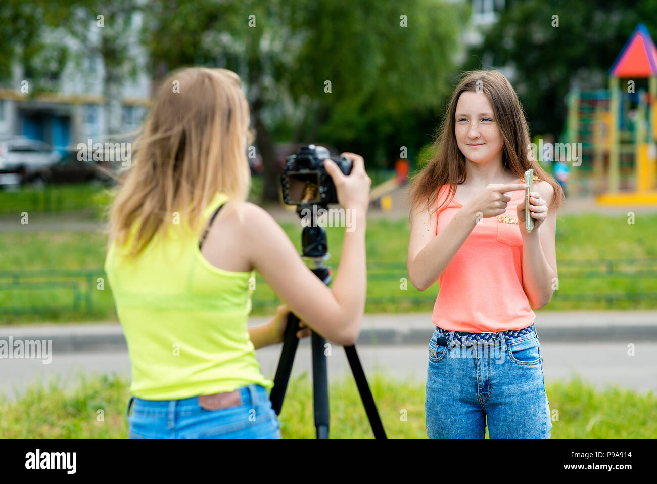 Due amiche, estate in natura. Registra un video sugli smartphone. Nelle mani tiene il telefono. Sorride felicemente. Utilizzare la fotocamera con treppiede. Foto Stock