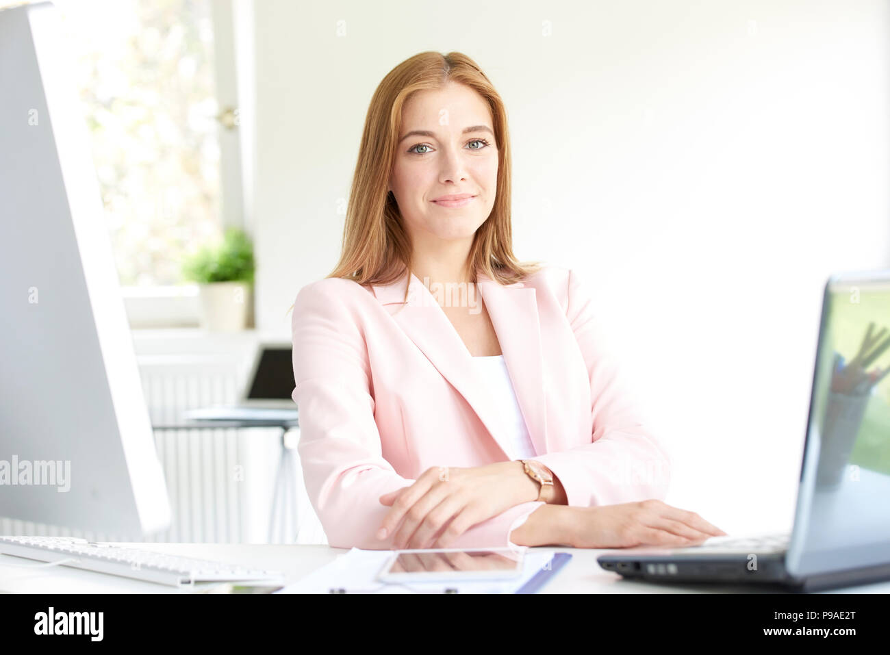Bellissima giovane assistente finanziario imprenditrice lavorando sul computer portatile mentre è seduto alla scrivania in ufficio. Foto Stock