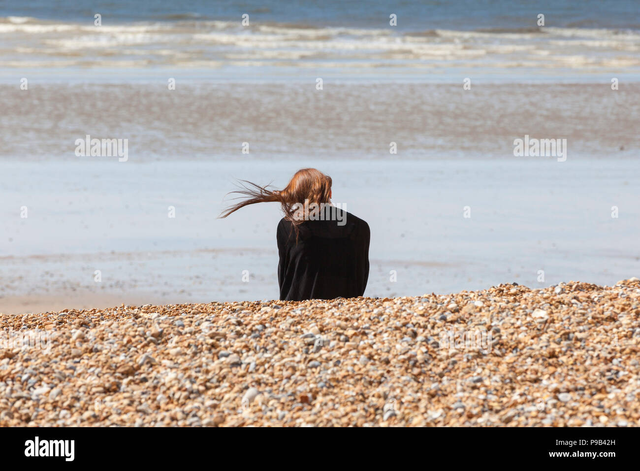 Hastings, East Sussex, Regno Unito. 17 lug 2018. Regno Unito Meteo: caldo e soleggiato in Hastings, East Sussex con nuvole intermittente ma una brezza di benvenuto nell'aria. Un sacco di persone stanno godendo della prolungata ondata di caldo continua a colpire la Gran Bretagna. Le temperature sono dovrebbe superare 25°C. Un sunbather seduto sulla spiaggia di Hastings godendo il sole caldo con la brezza del mare cattura i suoi capelli. (Con consenso). Photo credit: Paolo Lawrenson / Alamy Live News Foto Stock