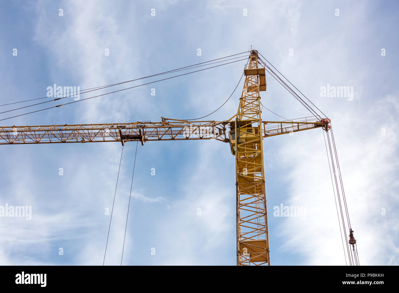 Giallo gru da cantiere contro nuvoloso cielo blu Foto Stock