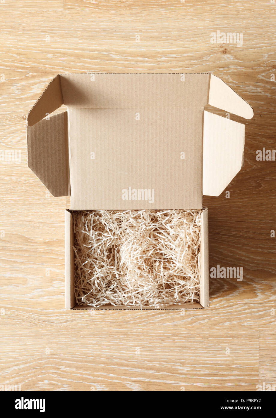 Ha aperto la scatola di cartone con legno excelsior riempitivo trinciatrice su sfondo di legno. Vista al di sopra Foto Stock