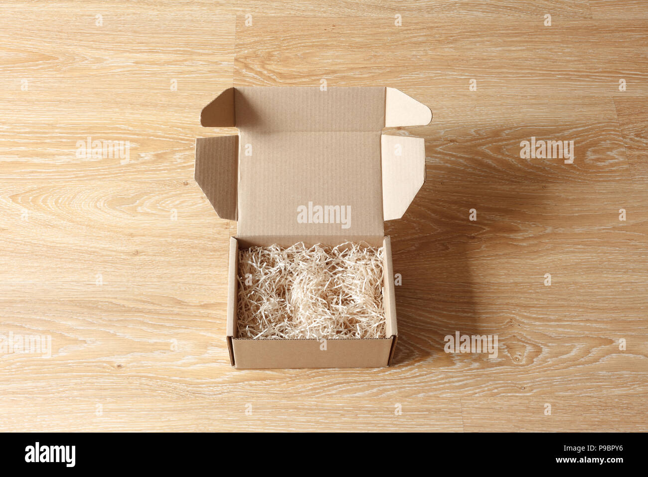 Ha aperto la scatola di cartone con legno excelsior riempitivo trinciatrice su sfondo di legno. Vista al di sopra Foto Stock