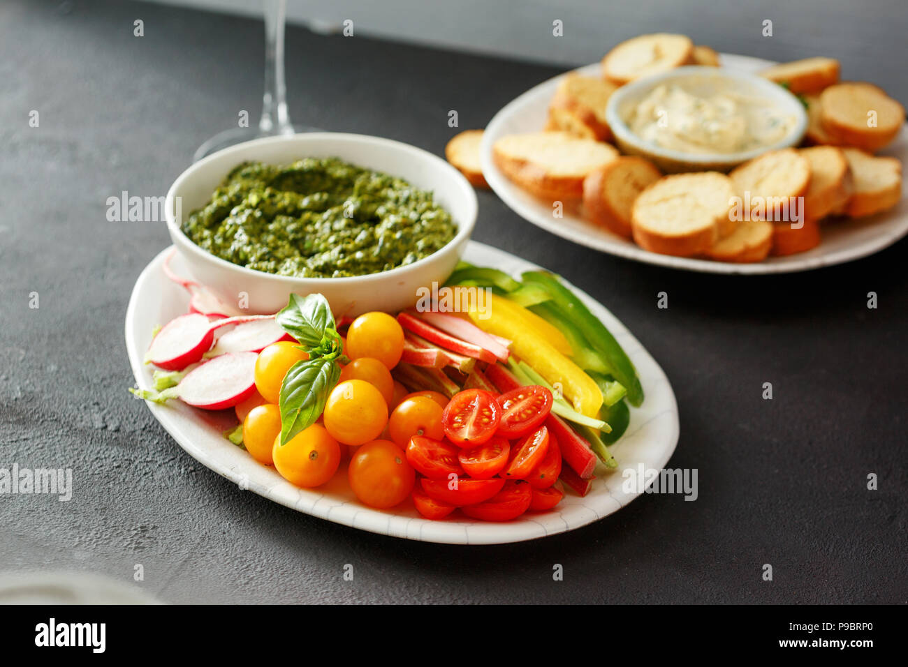 Snack sani per i vini. Verdure crude, crostini di pane con il pesto e salsa di aglio nero su sfondo di pietra Foto Stock