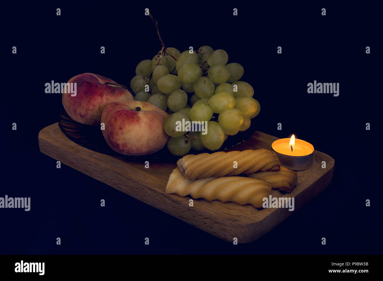 Ancora vita dalle tenebre. Composizione con frutta, torte e illuminazione delle candele. La qualità HD picture. Foto Stock