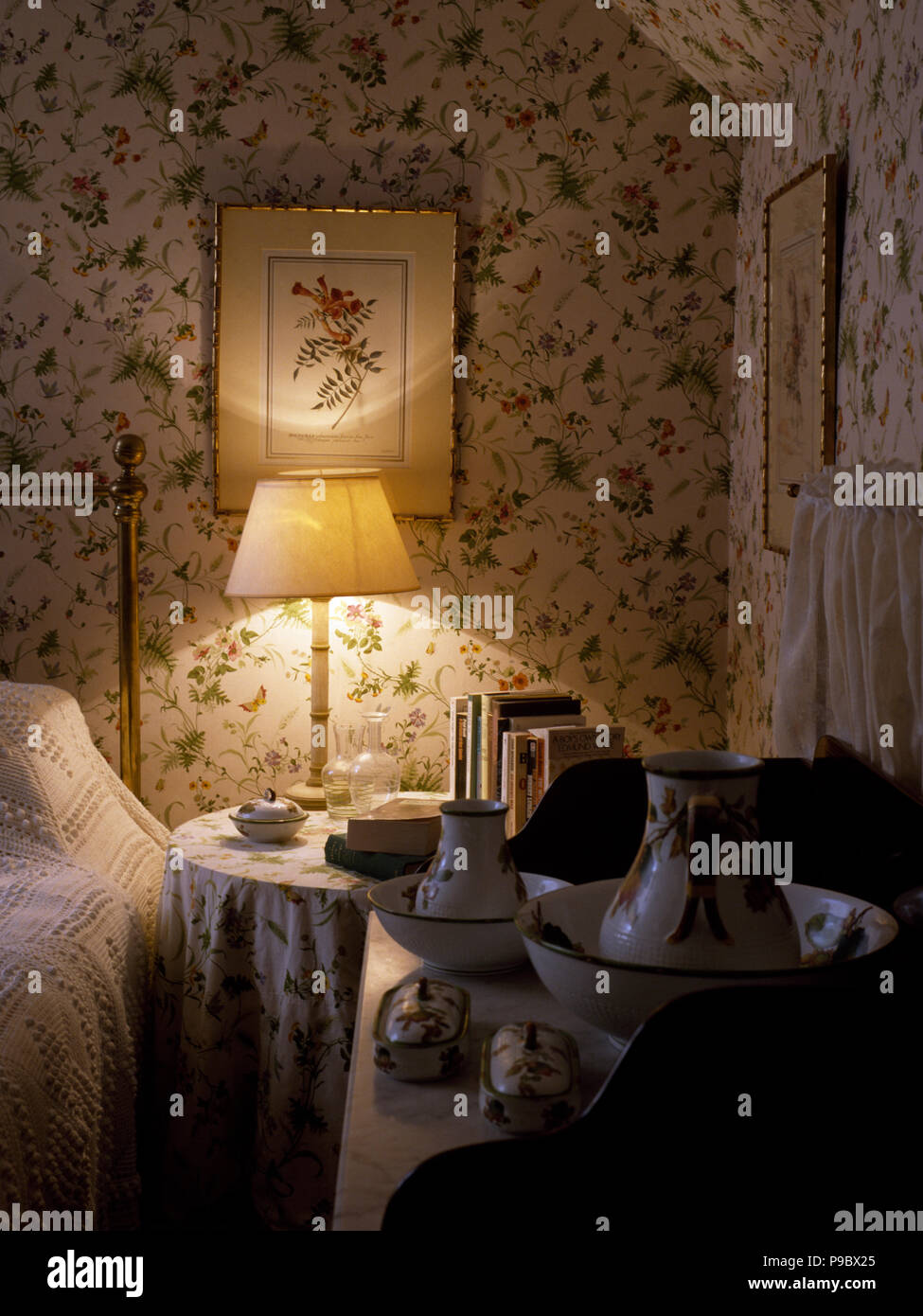Lampada accesa sul comodino in stile vittoriano, camera da letto con carta da parati floreale Foto Stock