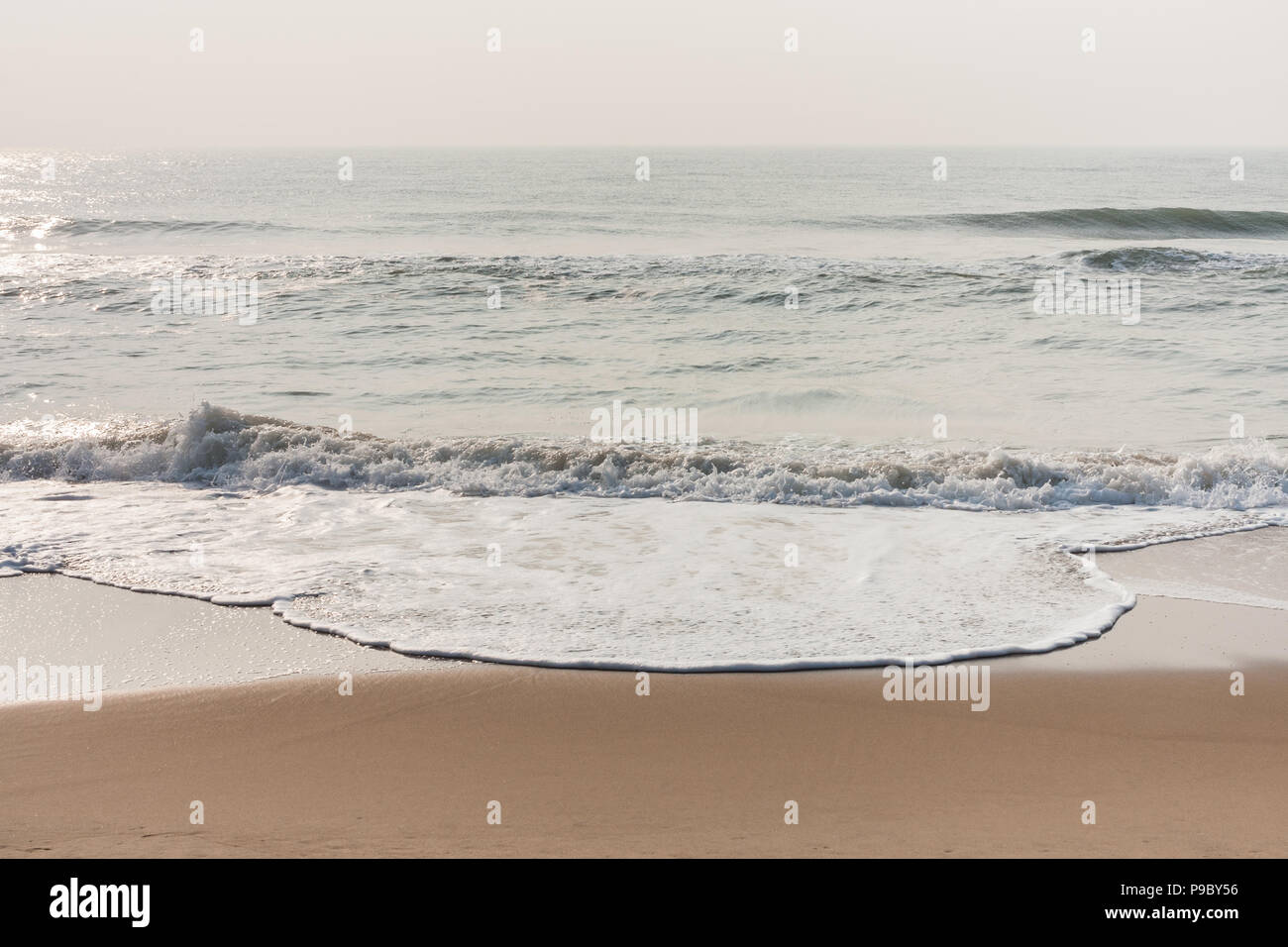 Spumeggianti onde sulla spiaggia tranquilla - schiumose onde del mare su una tranquilla spiaggia tropicale al mattino. Foto Stock