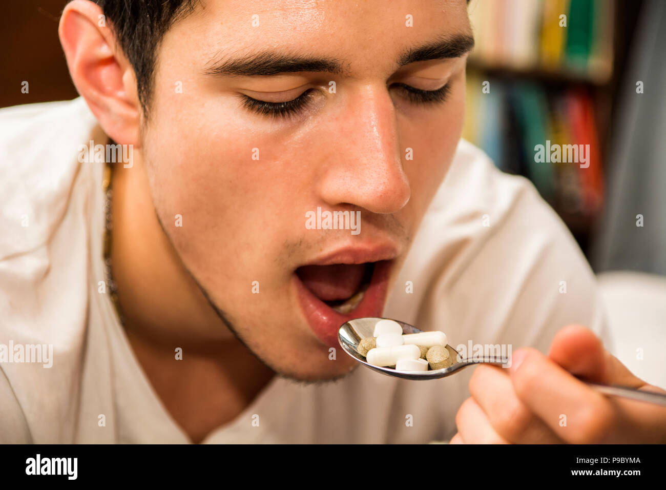Giovane uomo mangiare un cucchiaio colmo di medicina Foto Stock
