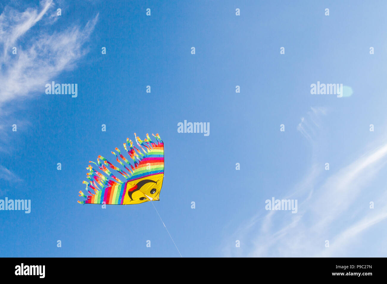 Un divertente e luminosa aquilone volante nel cielo blu Foto Stock