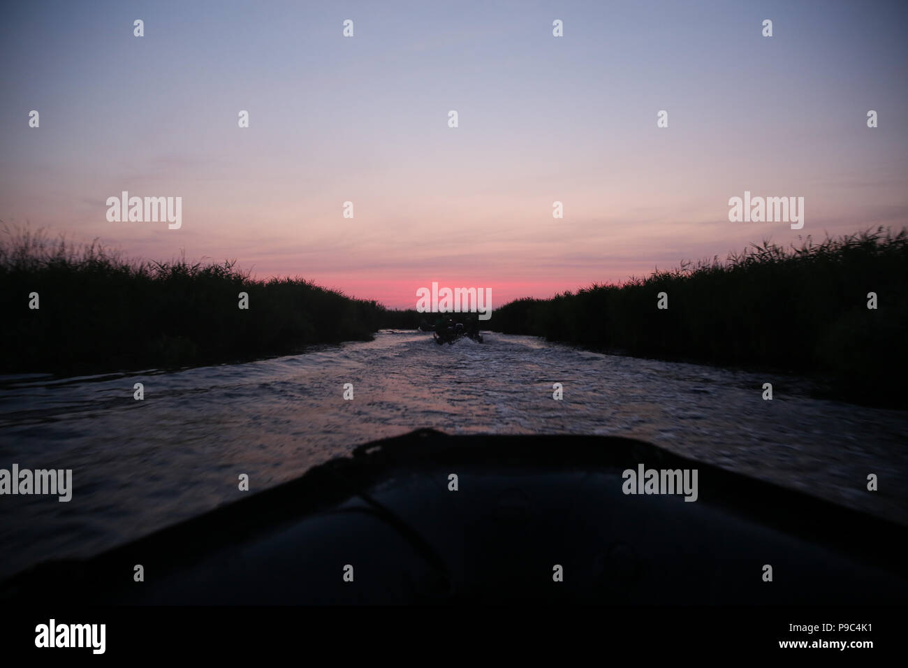 Sunrise visto da un accelerando la zattera in gomma su un lago nel sud della Romania Foto Stock