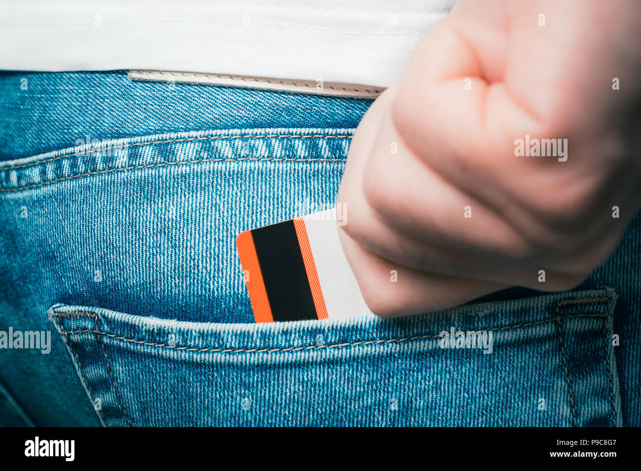 Maschio prendendola per mano di una carta bancaria nella tasca posteriore di un paio di jeans pantaloni Foto Stock