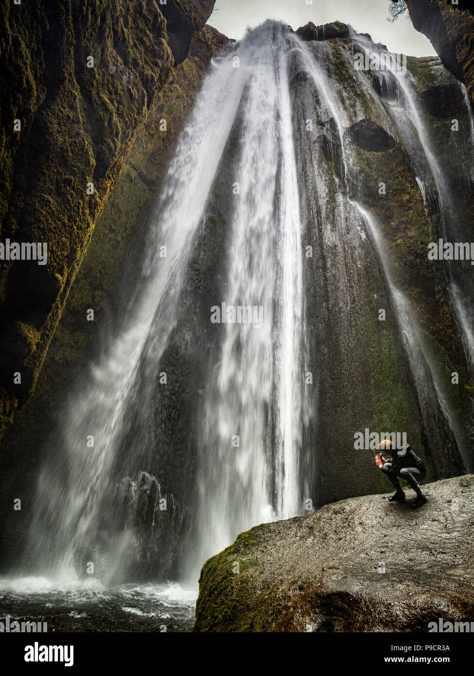 21 Aprile 2018: Sud Islanda - Gljufrabui cascata, e un uomo di scattare una foto con il suo telefono cellulare. Foto Stock