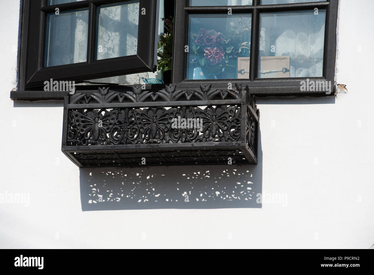 Fiore di metallo scatole di finestra su un vecchio bianco casa murata con interessanti modelli. Foto Stock