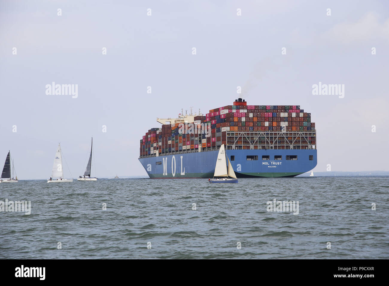 Mol la fiducia di portacontainer nel canale di spedizione off Cowes, Isle of Wight, con barca pilota leader di mercato Foto Stock