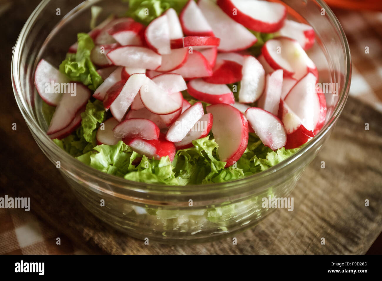 Vegano vegetali insalata di aglio selvatico, Rafano, cipolline, cavolo e lattuga in un grande piatto trasparente su un antico sullo sfondo di legno. Close-up Foto Stock