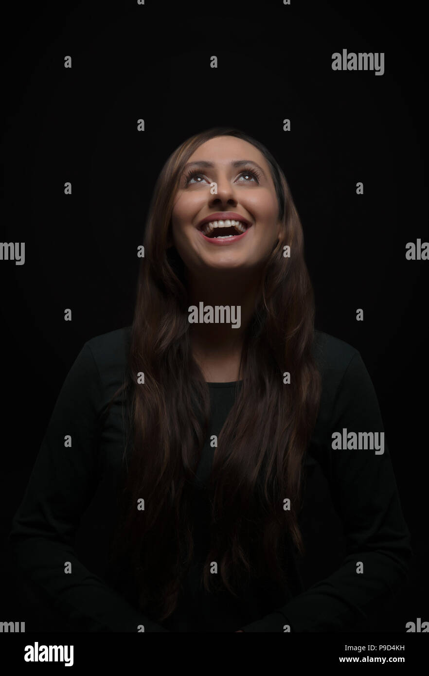 Ritratto di sorridente giovane donna che guarda verso l'alto Foto Stock