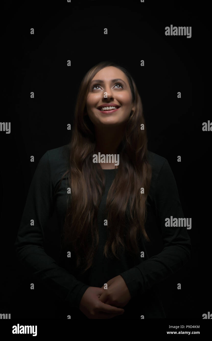 Ritratto di sorridente giovane donna che guarda verso l'alto Foto Stock