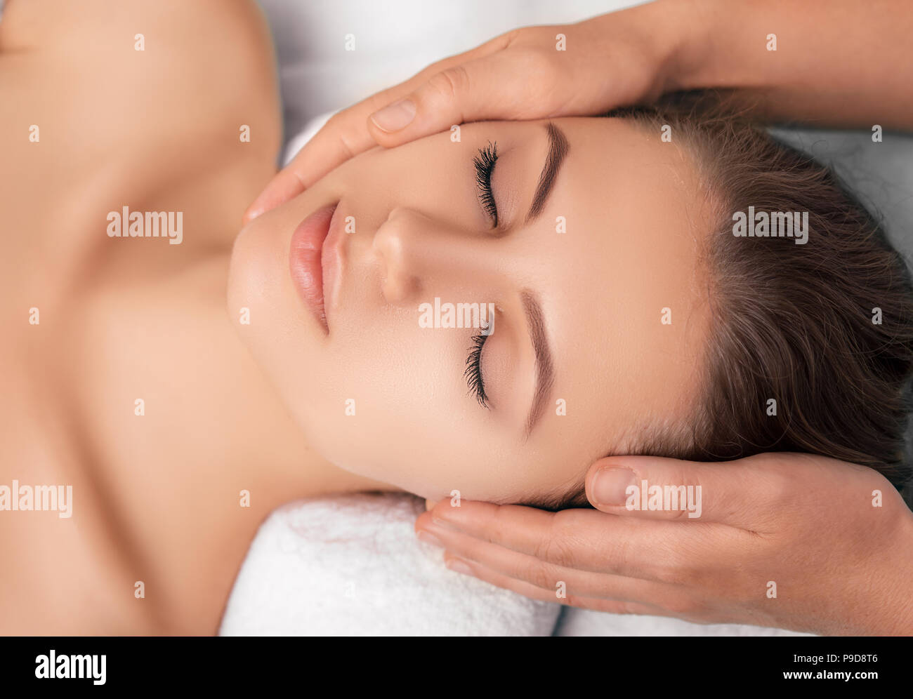 Vista da sopra attraente giovane donna che gode di una bellezza trattamento del viso in una spa, close-up viso con perfetta pelle fresca Foto Stock