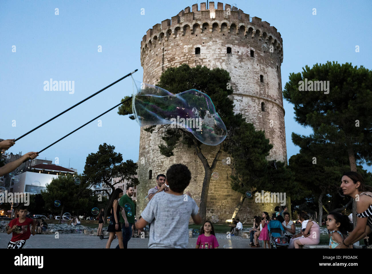 I bambini giocano con le bolle di sapone sotto il distintivo della città, la Torre Bianca, sul lungomare di Salonicco Grecia il 16 luglio 2018. Foto Stock