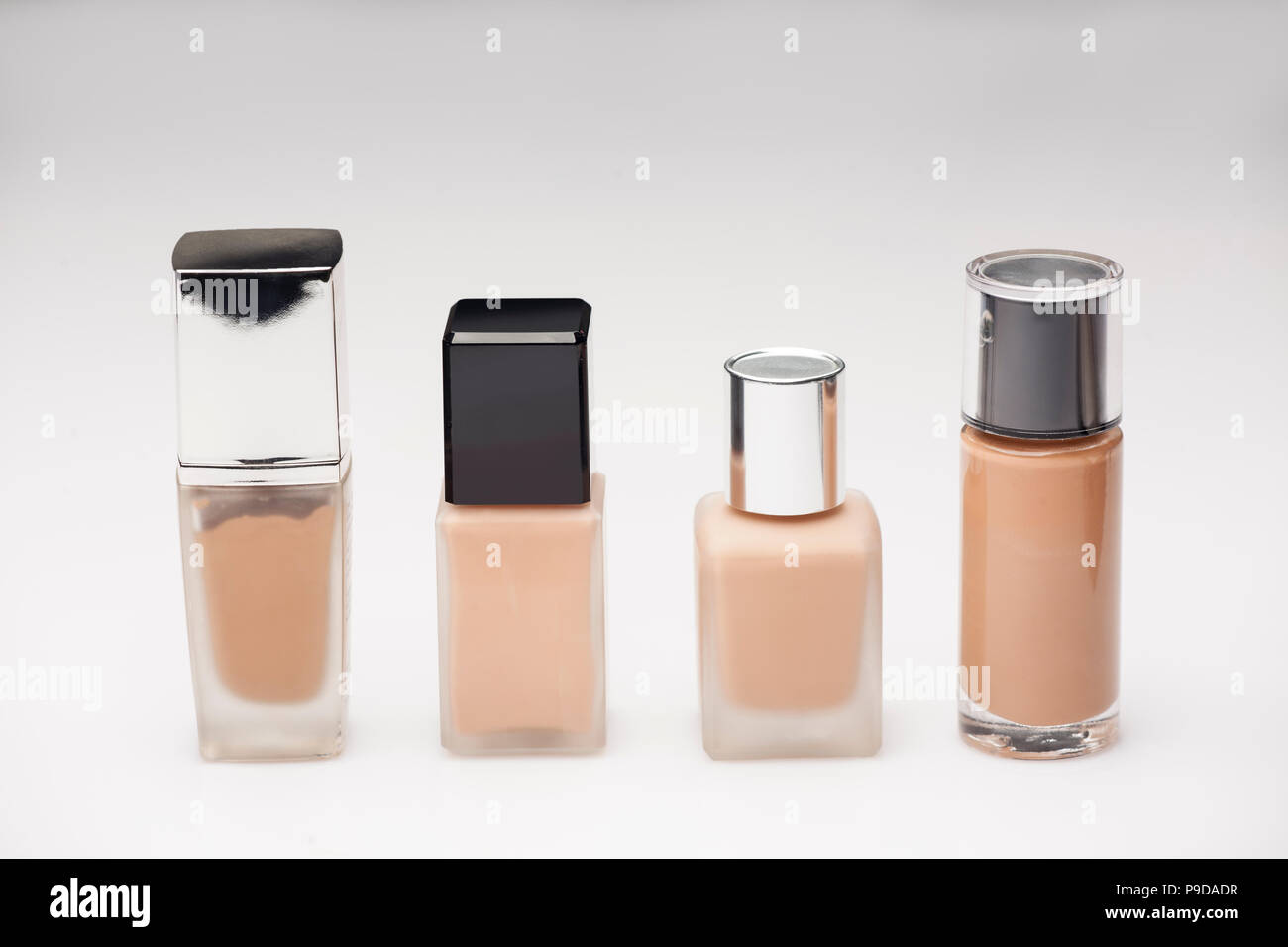 Diverse bottiglie con liquidi foundation su sfondo bianco Foto Stock