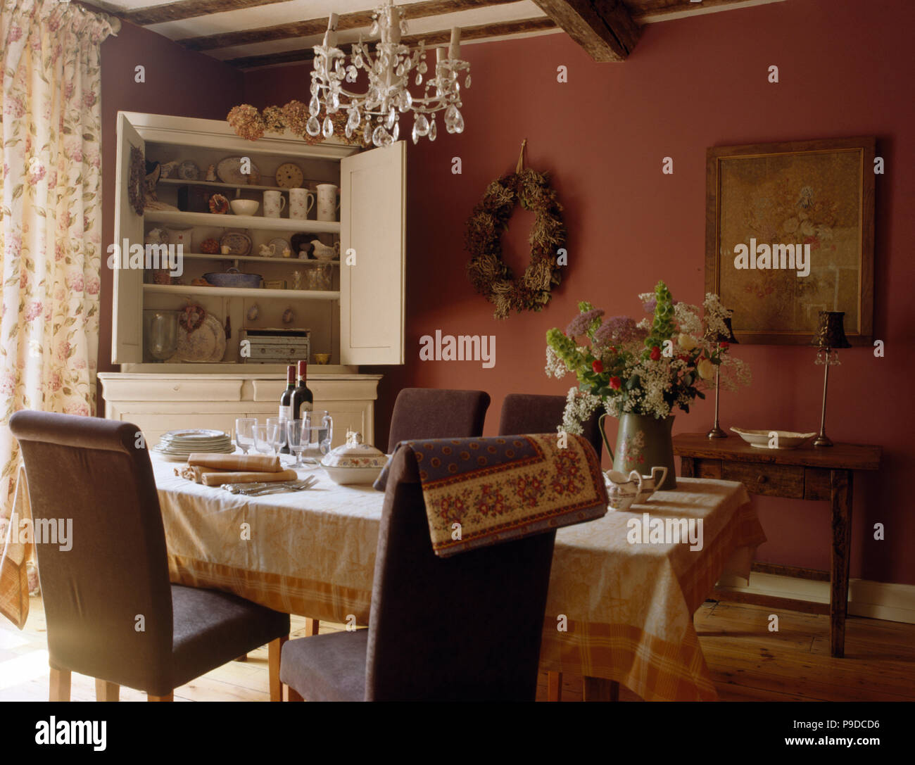 Grigio sedie imbottite a tavola con una crema di panno modellato in un cottage rosa sala da pranzo Foto Stock