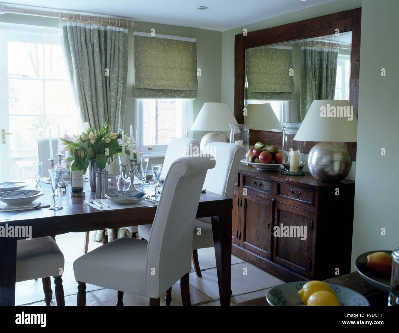 White sedie imbottite a tavola insieme per il pranzo a townhouse sala da  pranzo con un grande specchio sopra credenza Foto stock - Alamy