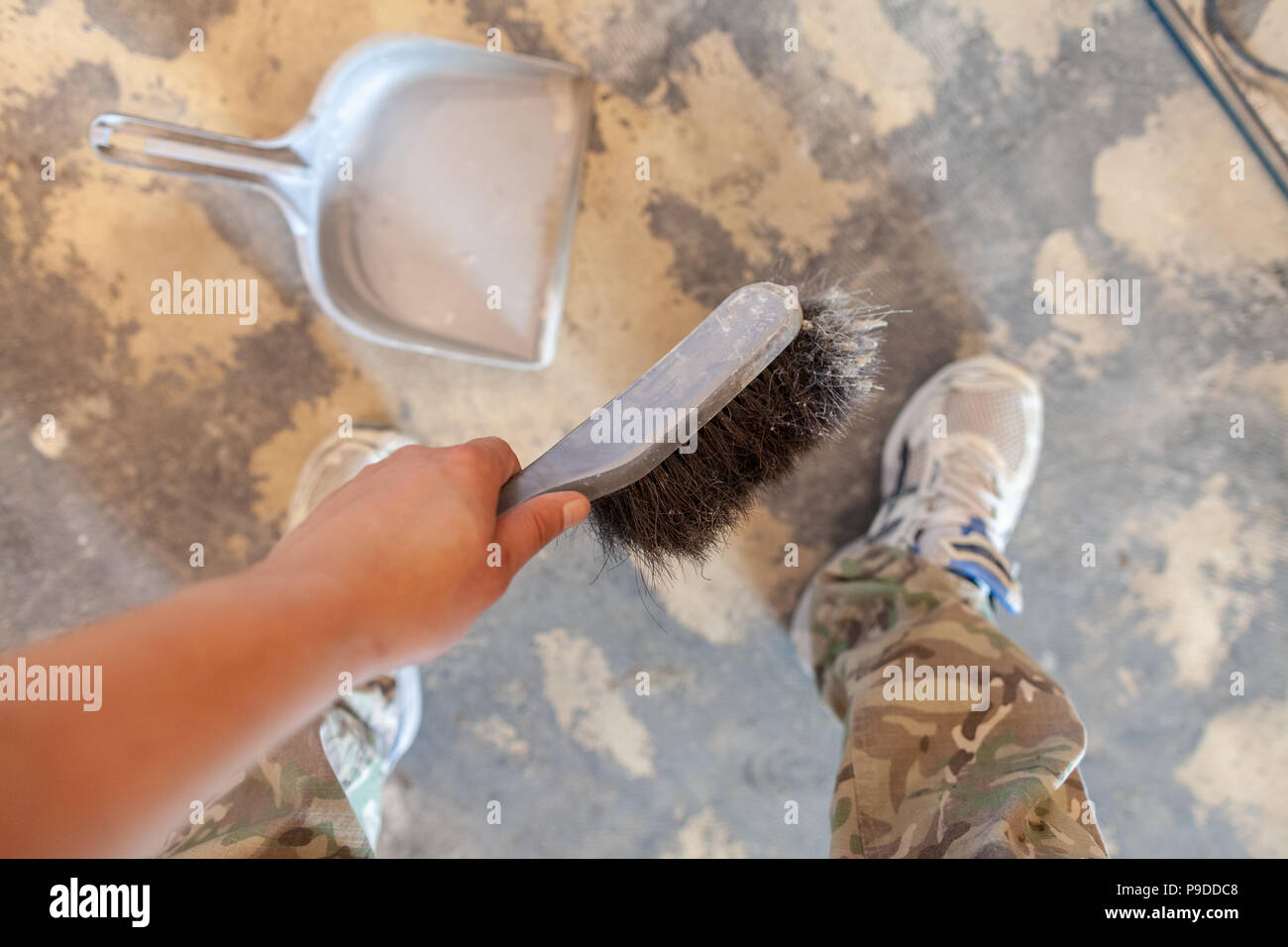 Mano impugna una scopa a mano sul lato della costruzione Foto Stock