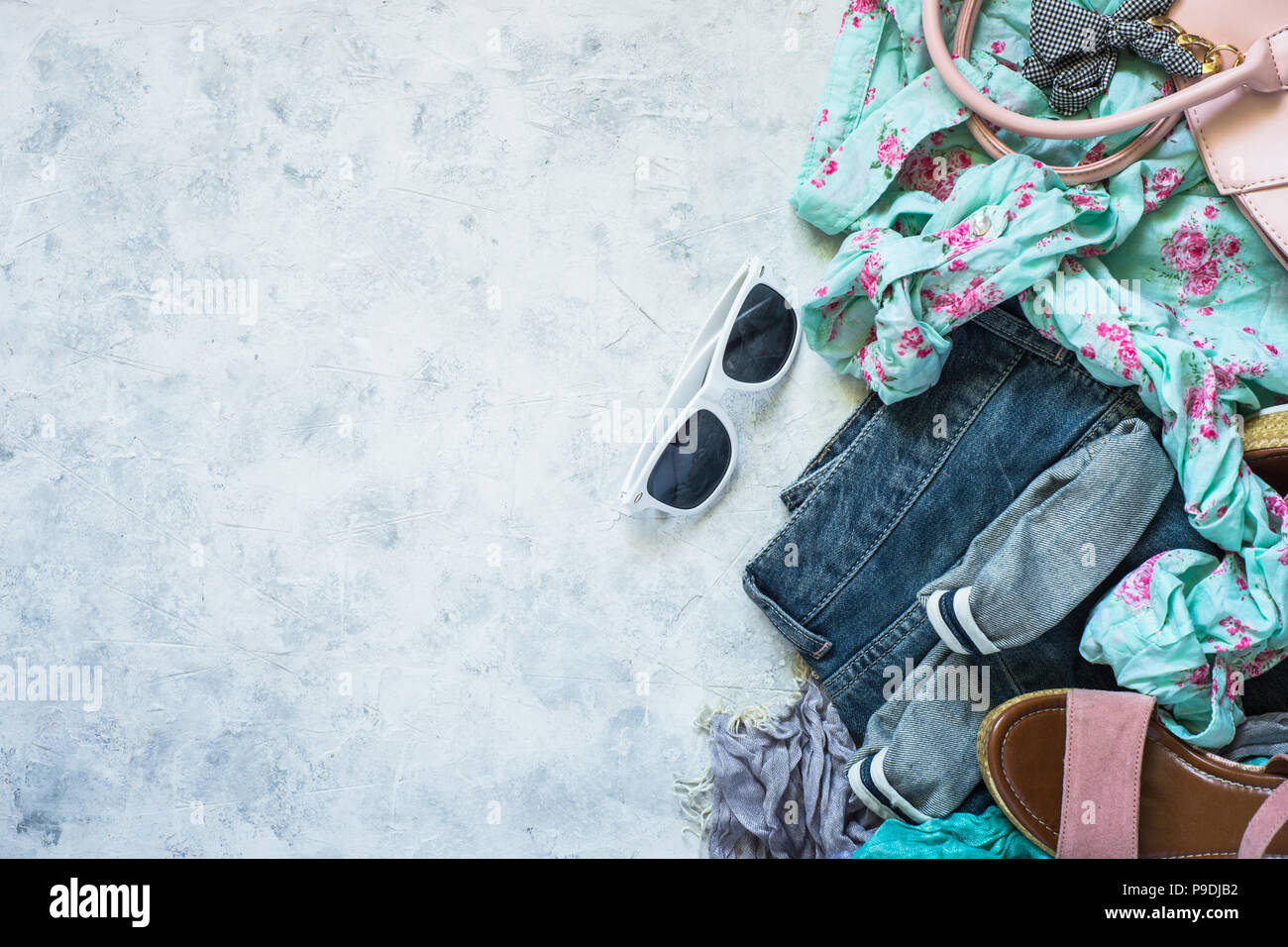 Abiti donna e accessori jeans, camicetta, occhiali da sole, sandali e borsa su sfondo di pietra. Moda & Bellezza dello sfondo. Look moderno. Piatto copia laici sp Foto Stock