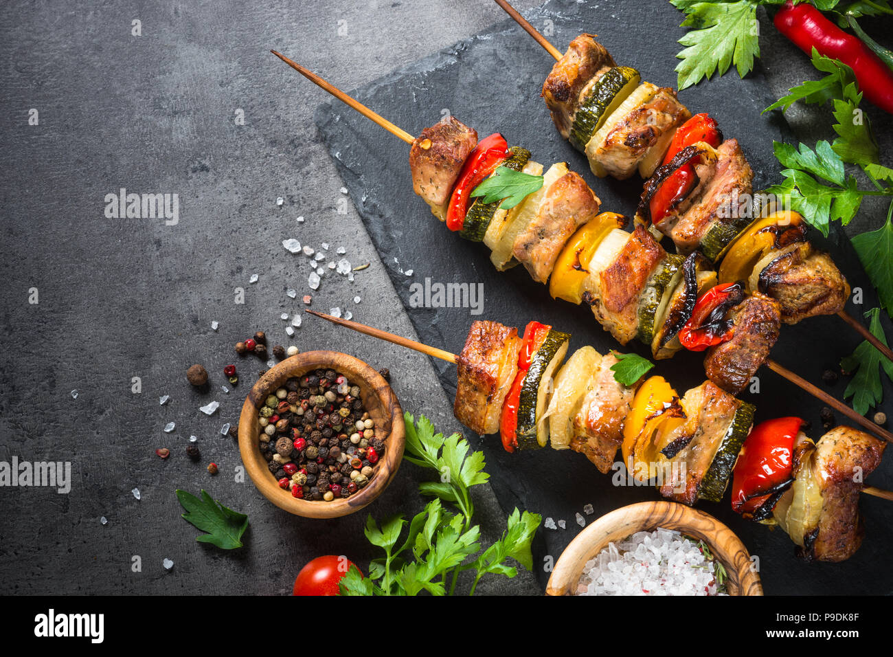 Grigliata di shish kebab o spiedini con verdure su nero tavolo di pietra. La carne di maiale. Grigliata di carne. Vista dall'alto uno spazio di copia. Foto Stock