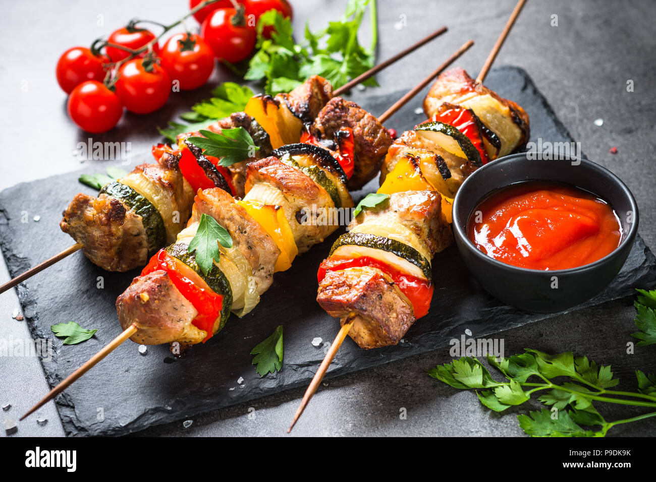 Grigliata di shish kebab o spiedini con verdure su nero tavolo di pietra. La carne di maiale. Grigliata di carne. Foto Stock
