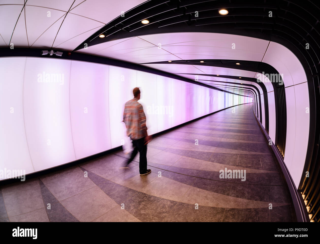 Uomo che cammina in lit-up tunnel che collega stazione ferroviaria internazionale di St Pancras e di King Cross a Londra Foto Stock