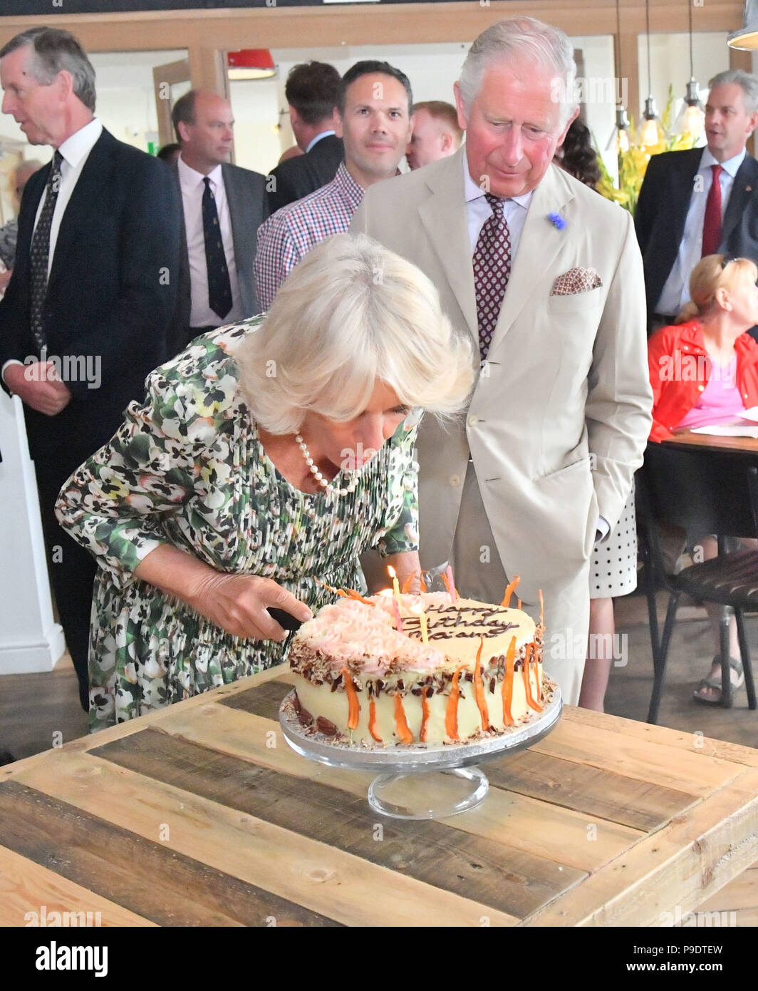 La duchessa di Cornovaglia si brucia candele su una torta che celebra il suo 71esimo compleanno come ella visite Cafe sul Quay con il Principe di Galles durante la loro visita a Santa Maria, Isole Scilly. Foto Stock