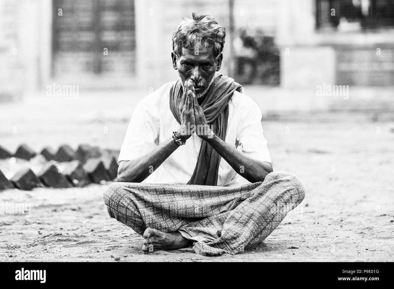 PUDUCHERY, Pondicherry, Tami Nadu, India - SETTEMBRE CIRCA, 2017. Un uomo non identificato si siede con le gambe incrociate e le mani meditando davanti a un indù Foto Stock