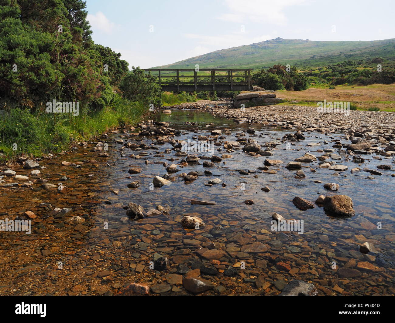 Passerella sul fiume Lyd con acqua cristallina e rocce e Dartmoor Foto Stock