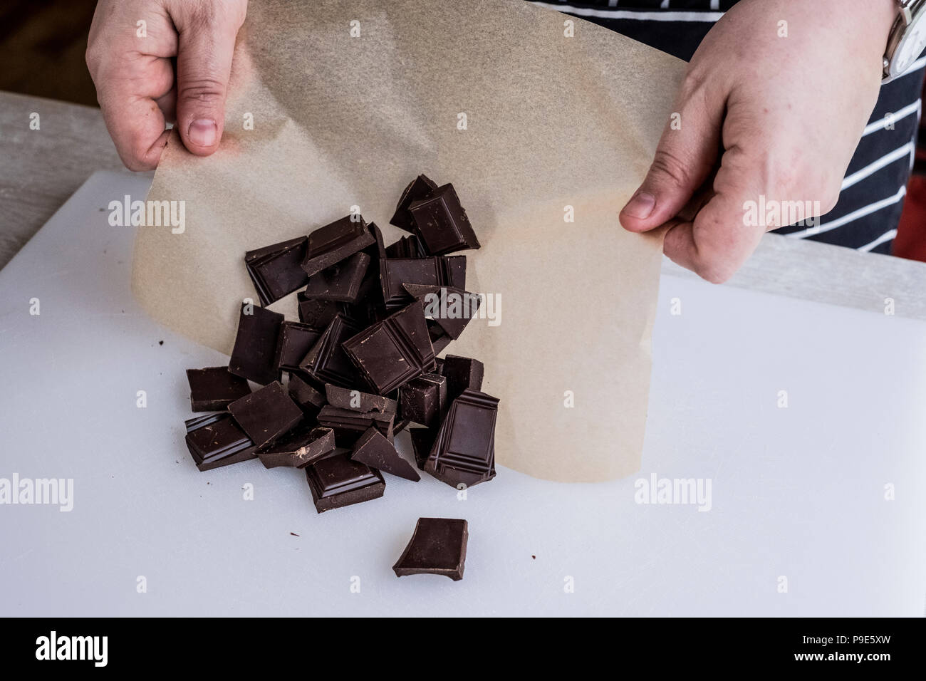 Un cuoco pesati con pezzetti di cioccolato sulla carta oleata. Foto Stock
