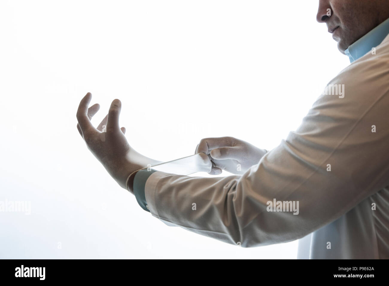 Un dentista tirando su un esame medico guanto. Foto Stock