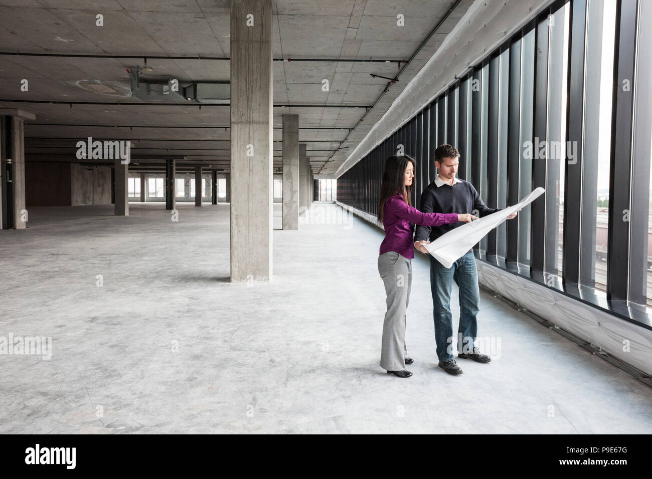 Due architetti che lavorano su dei piani aziendali in una nuova materie spazio commerciale. Foto Stock