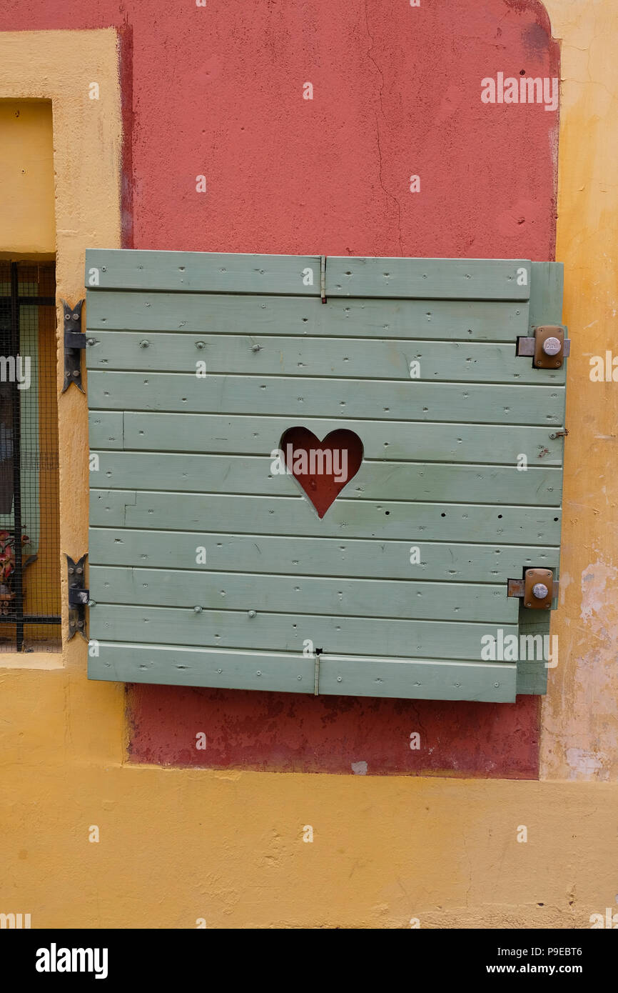 Nizza, Francia. Attraente piccola finestra in legno con otturatore a forma di cuore tagliato fuori dal centro Foto Stock