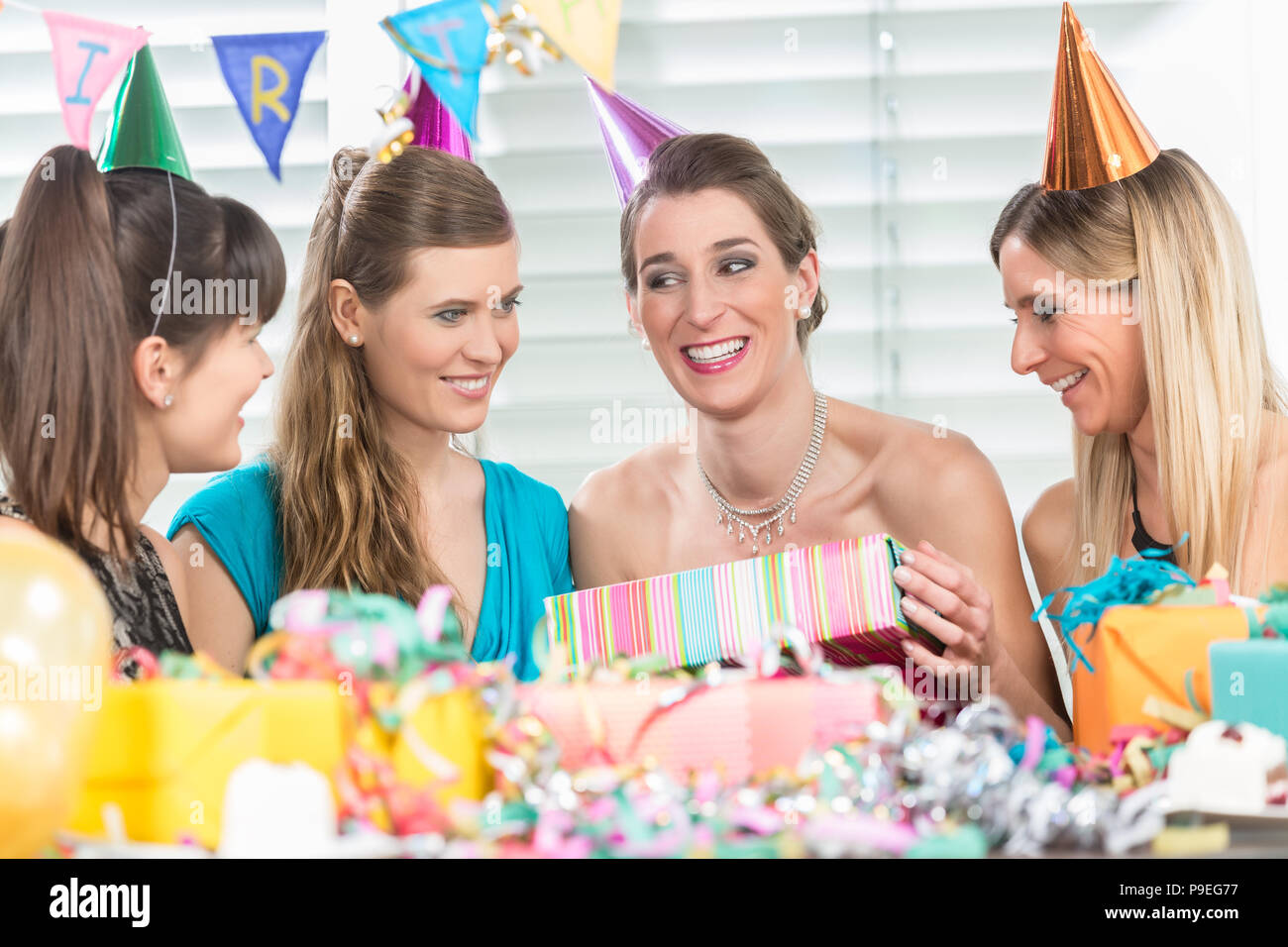 Donna allegra tenendo un regalo durante una sorpresa festa di compleanno Foto Stock