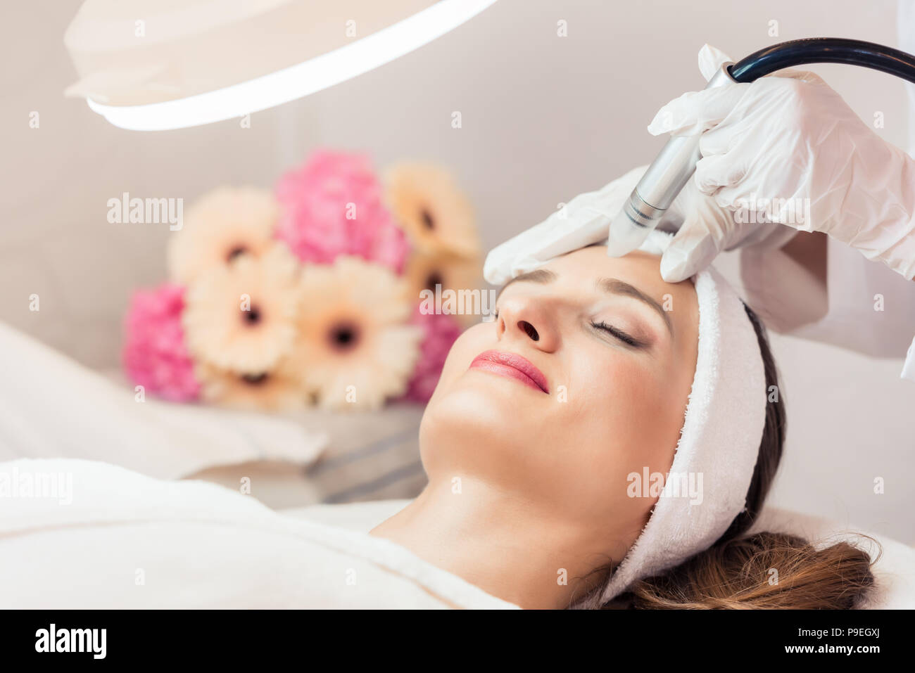 Close-up del volto di una bella donna sorridente durante il trattamento del viso Foto Stock