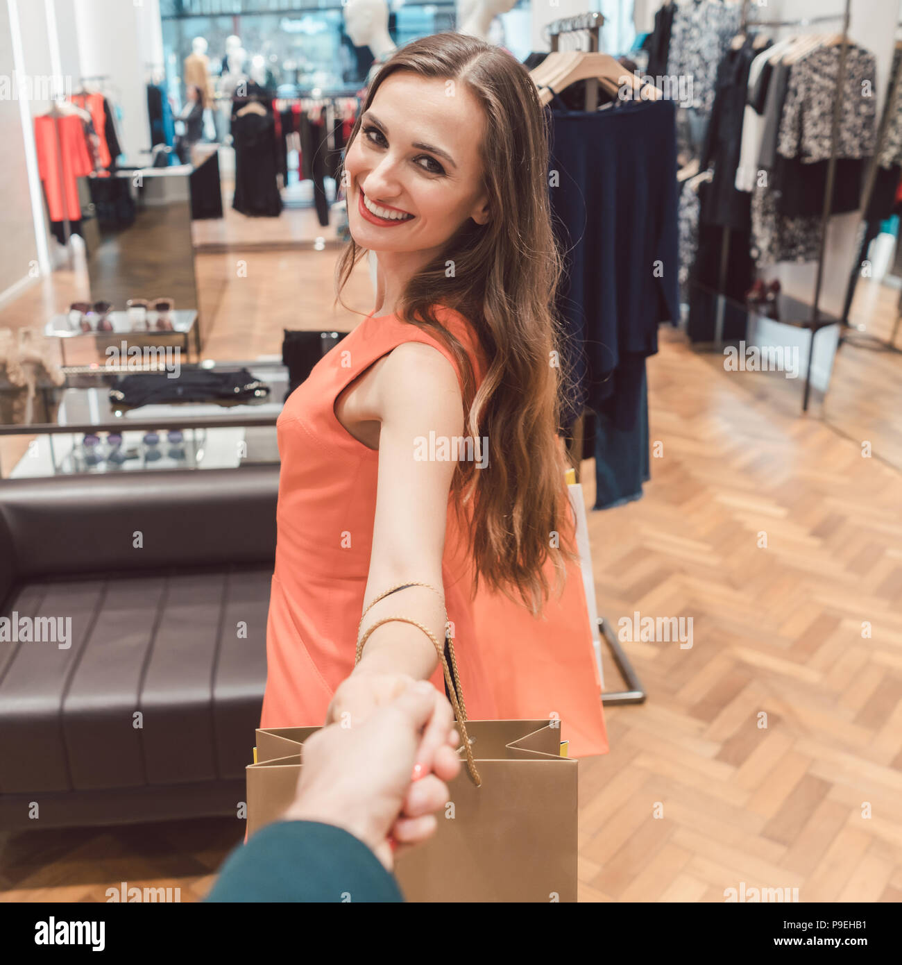 Donna trascinando il suo uomo di moda shopping nelle boutique o negozio Foto Stock