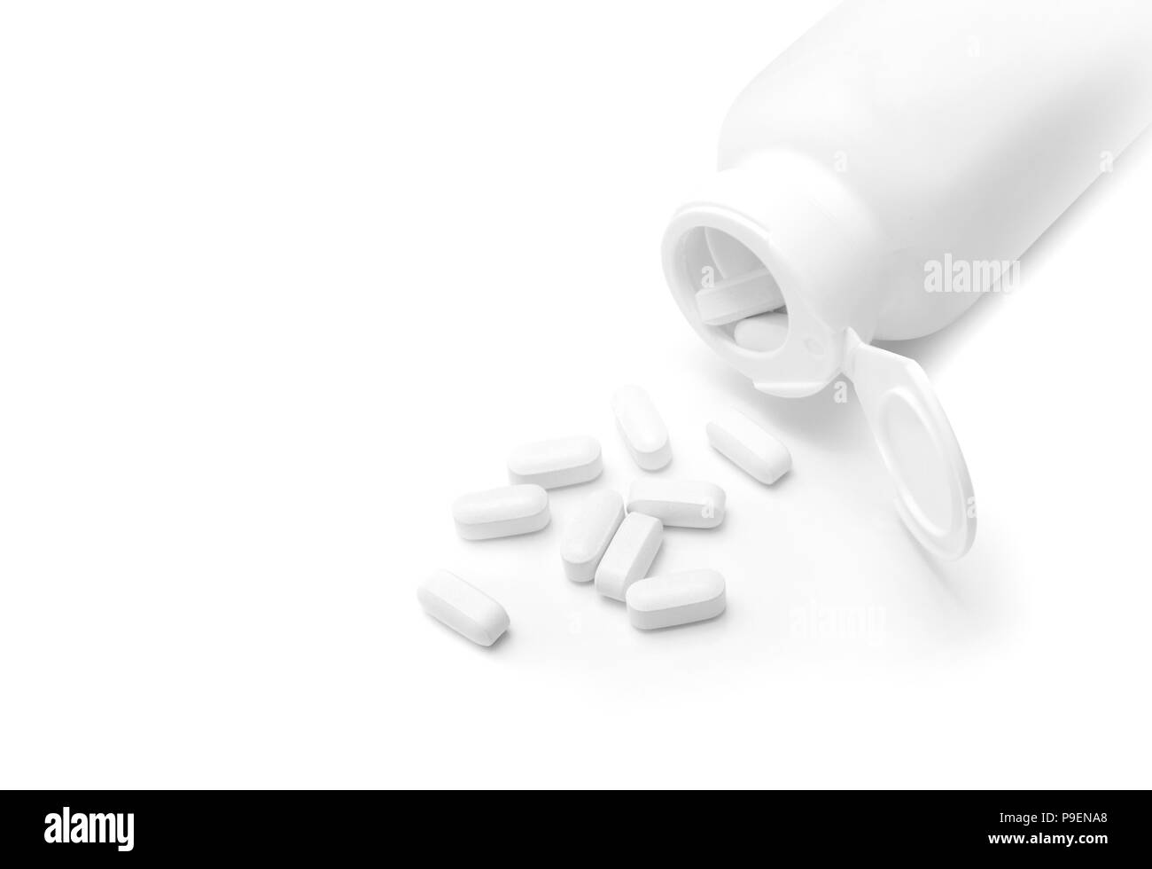 Pillole di bianco si versato da una bottiglia aperta Foto Stock