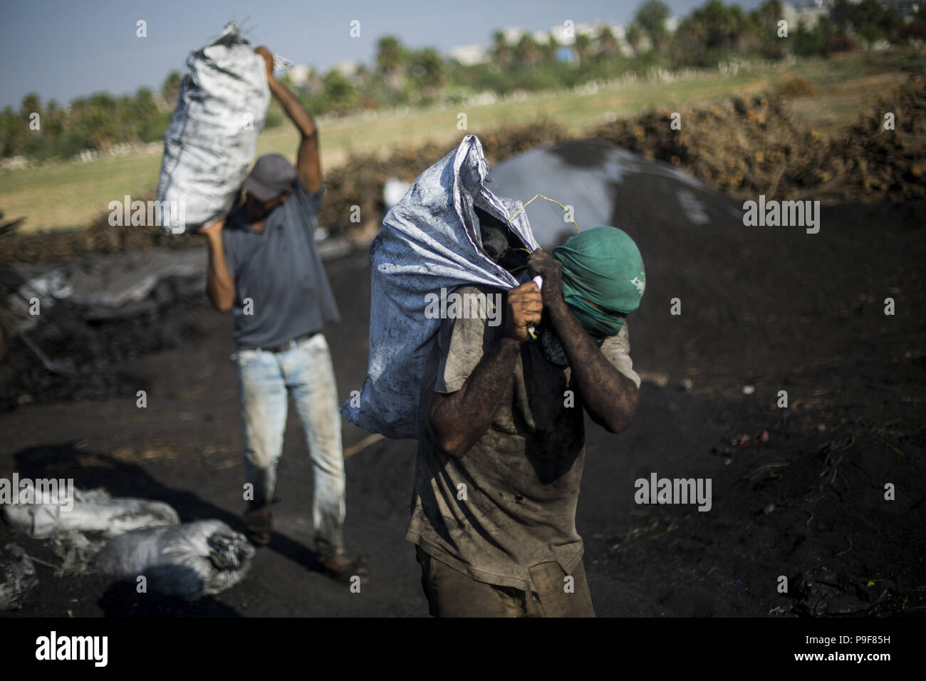 Luglio 18, 2018 - Gaza City, la striscia di Gaza, la Palestina - un palestinese il concessionario detiene un sacco di carbone dopo l'acquisto di esso al Hattab stabilimento di produzione, a est di Jabaliya Refugee Camp, nel nord della Striscia di Gaza City, nella Striscia di Gaza, il 18 luglio 2018. Hattab è il più grande produttore nella Striscia di Gaza. Cinque gli uomini lavorano tutto l'anno, soprattutto durante il periodo invernale e i periodi di vacanza quando la domanda di carbone è alta. Mentre i lavoratori tagliare diversi tipi di alberi, il legno viene utilizzato spesso per rendere il carbone. Albero di agrume è molto utile e costoso, ma Habash i lavoratori non installarlo su questo tipo solo e trattare con dispon Foto Stock