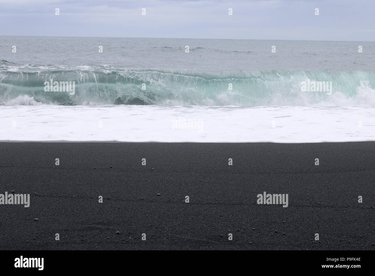 Le onde di laminazione sulla spiaggia nera di Reynisfjara, Islanda Foto Stock