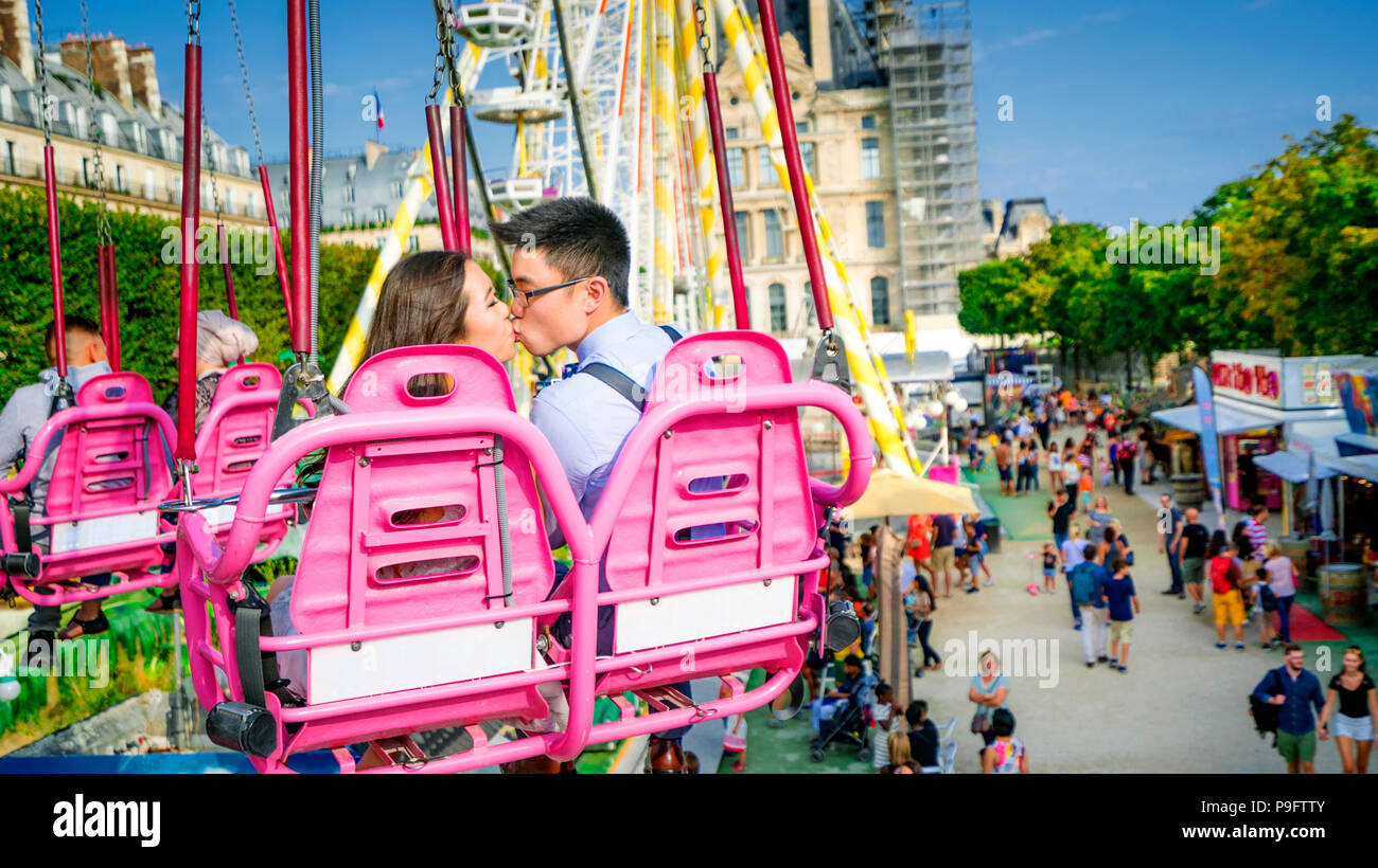 Una bella coppia asiatica bacia sulle sedie oscillanti nella Fete des Tuileries a Parigi, Francia Foto Stock