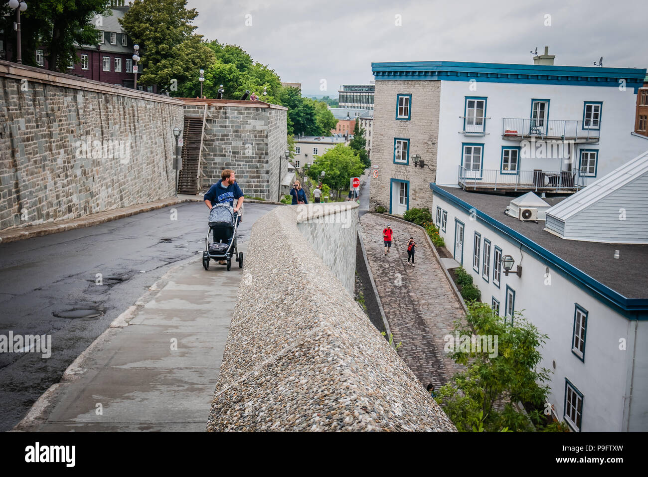 Uomo di spingere un passeggino in salita Foto Stock